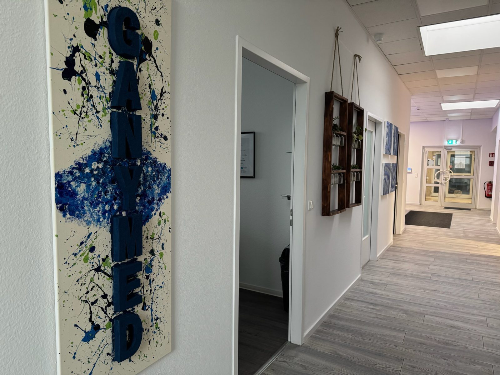 Heller Flur in den Räumen der Gany.MED GmbH mit blauem Gany.MED-Wandbild